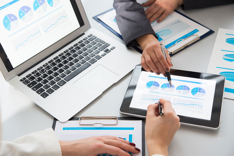 Financial provider discussing revenue statements with a laptop and tablet.