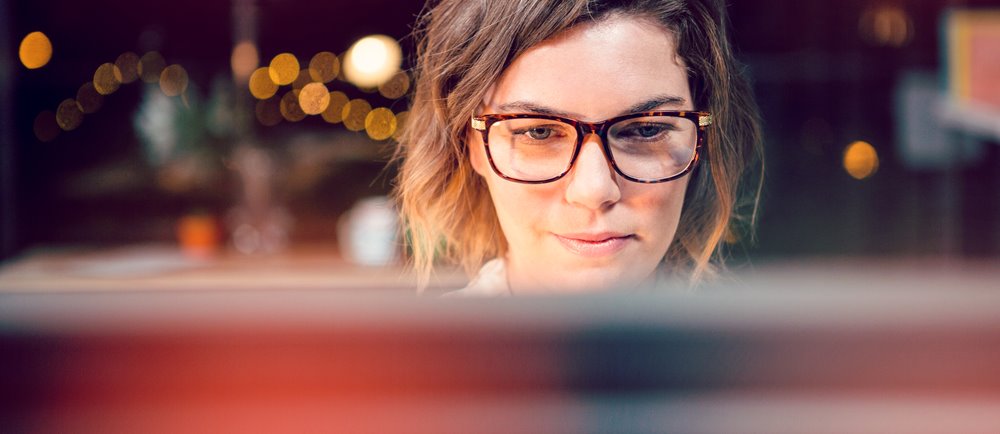 Young woman looking at laptop screen while sitting in a coffee shop.