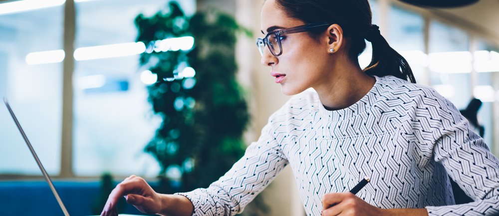 Woman reviewing website and sitting at a desk in her office building.