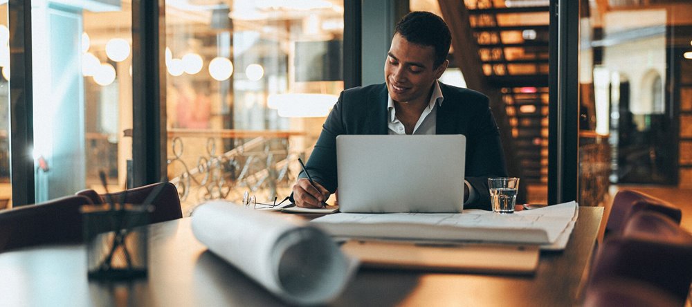 Business man sitting at office desk while reviewing dates on calendar.