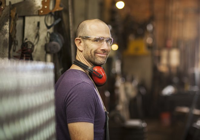 Male employee smiling while working in an industrial shop.