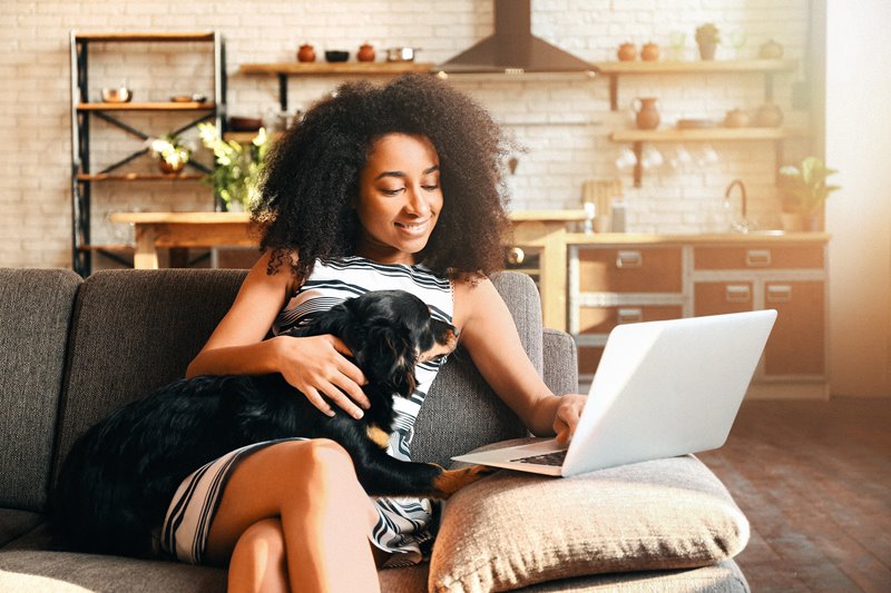 Woman and her dog relaxing on a couch while reviewing simplified retirement plan options by Principal.