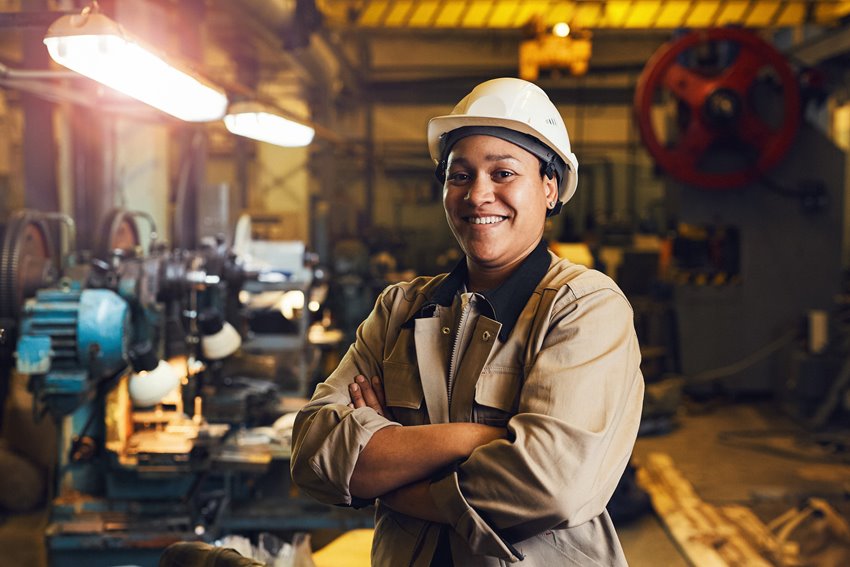Woman smiling while standing at her station in an industrial factory.