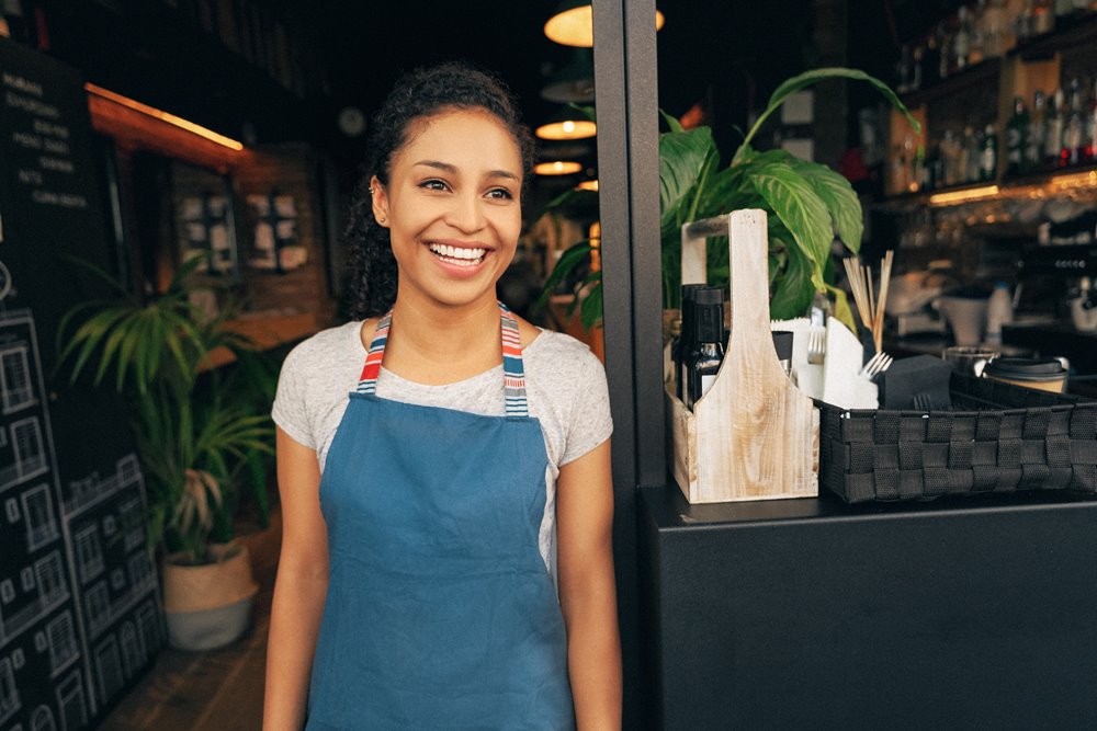 young woman and business owner smiling while working at her small market business. 