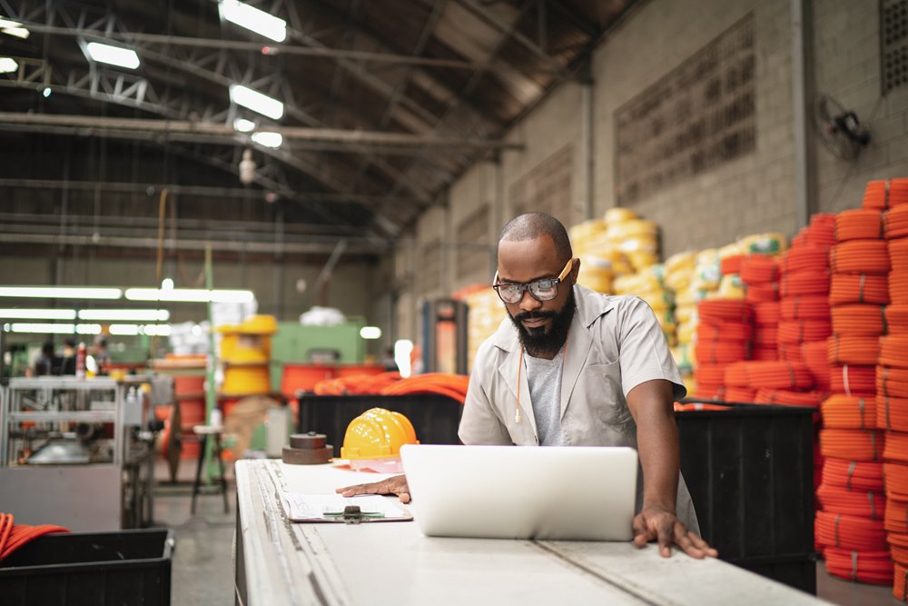 Male employee reviewing project timelines on his laptop while in the factory.