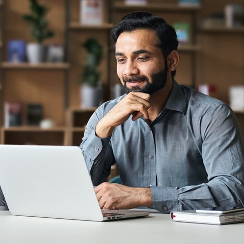 Financial professional reading his laptop screen while smiling.